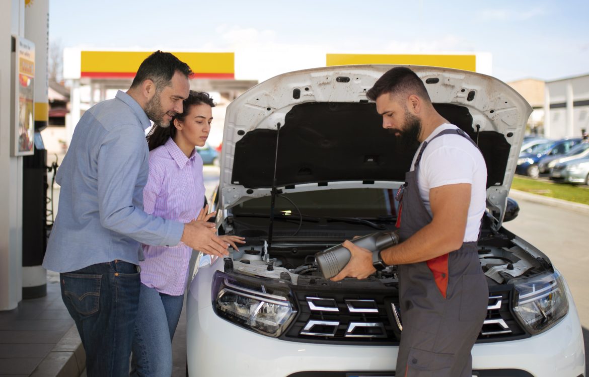 Mechanic in Colombia explaining automotive battery replacement signs to car owners at a service station