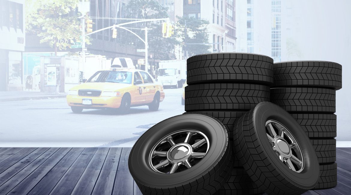 Stacks of commercial vehicle tires on wooden floor with city taxi in the background — ideal for radial vs bias ply tire comparison.