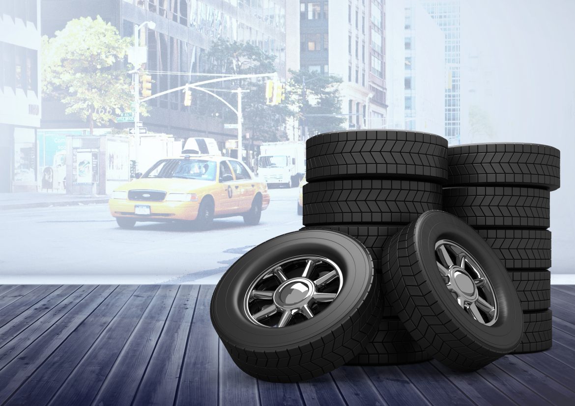 Stacks of commercial vehicle tires on wooden floor with city taxi in the background — ideal for radial vs bias ply tire comparison.