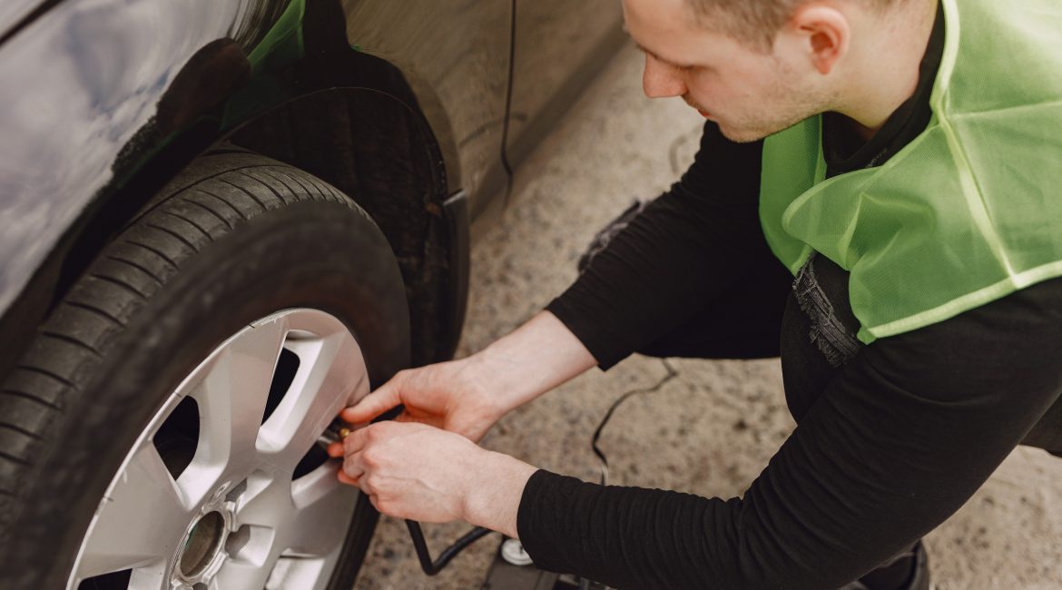 Man checking tire pressure on a car using a portable gauge — maintaining optimal pressure in PCR tires for safety and efficiency.
