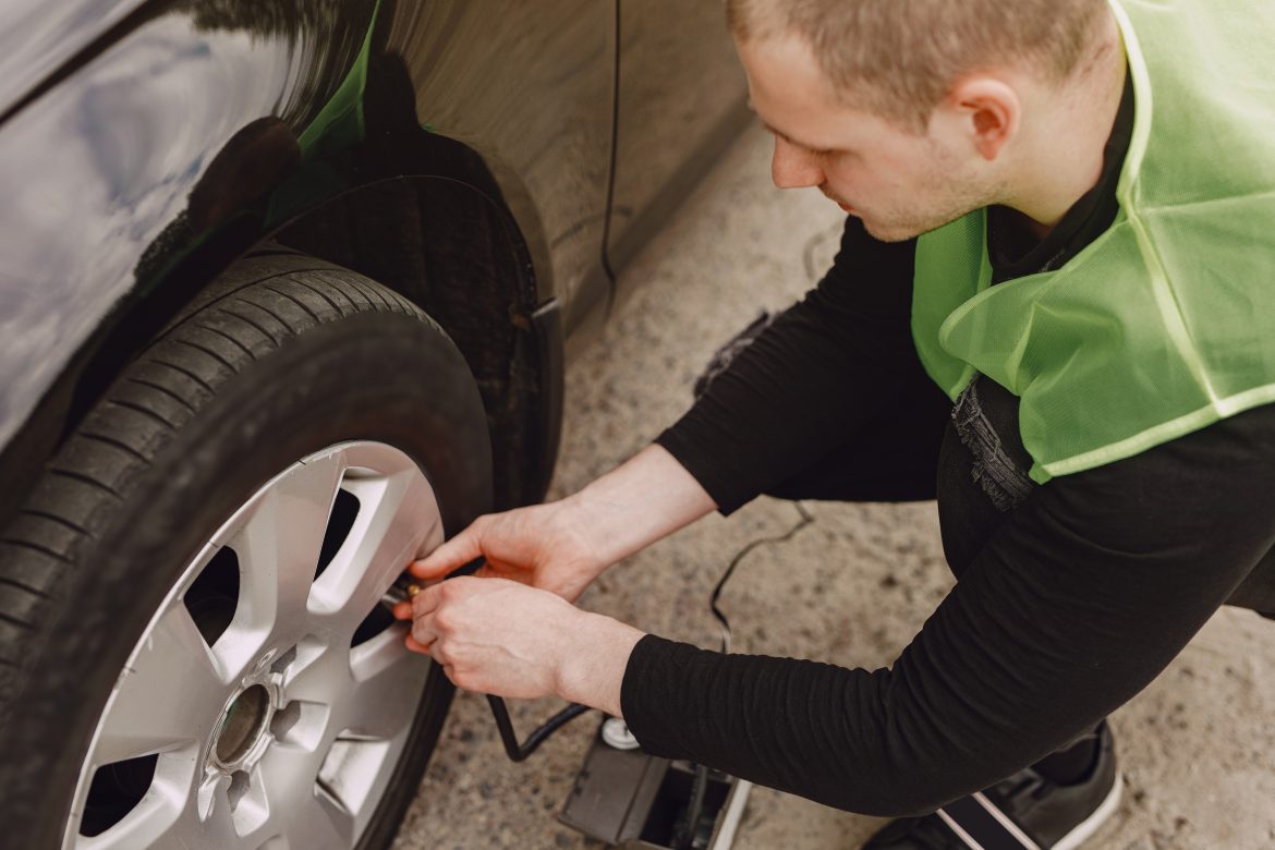 Man checking tire pressure on a car using a portable gauge — maintaining optimal pressure in PCR tires for safety and efficiency.