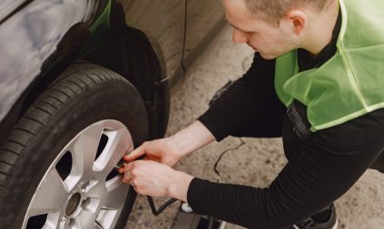 Man checking tire pressure on a car using a portable gauge — maintaining optimal pressure in PCR tires for safety and efficiency.